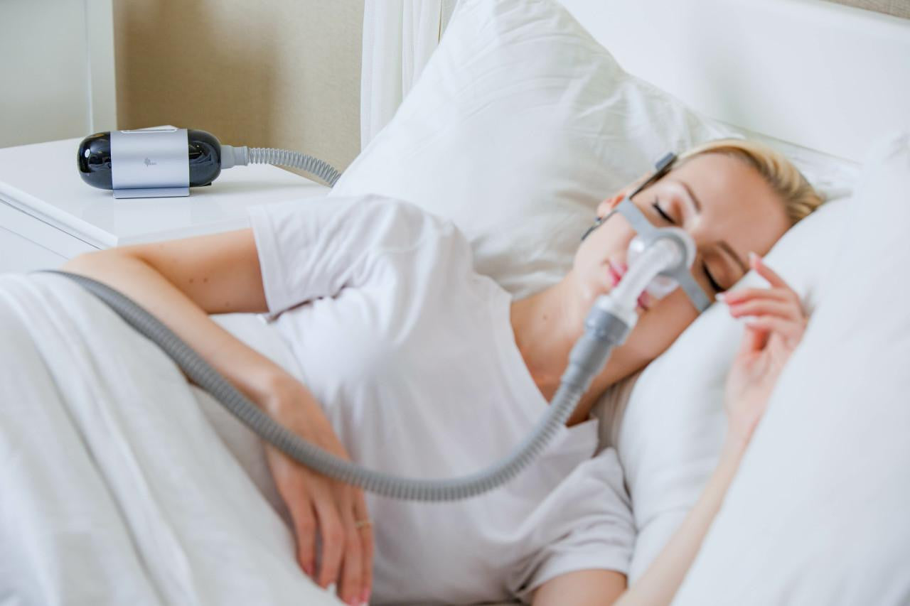 BMC M1 Travel Auto CPAP, a woman sleeping with a CPAP mask on her face.