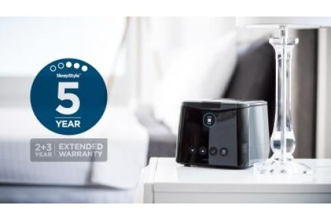 Fisher and Paykel Healthcare F&P Extended Care CPAP Warranty Card, close-up image of the warranty card placed on a bedside table with a CPAP machine and glass of water in the background.
