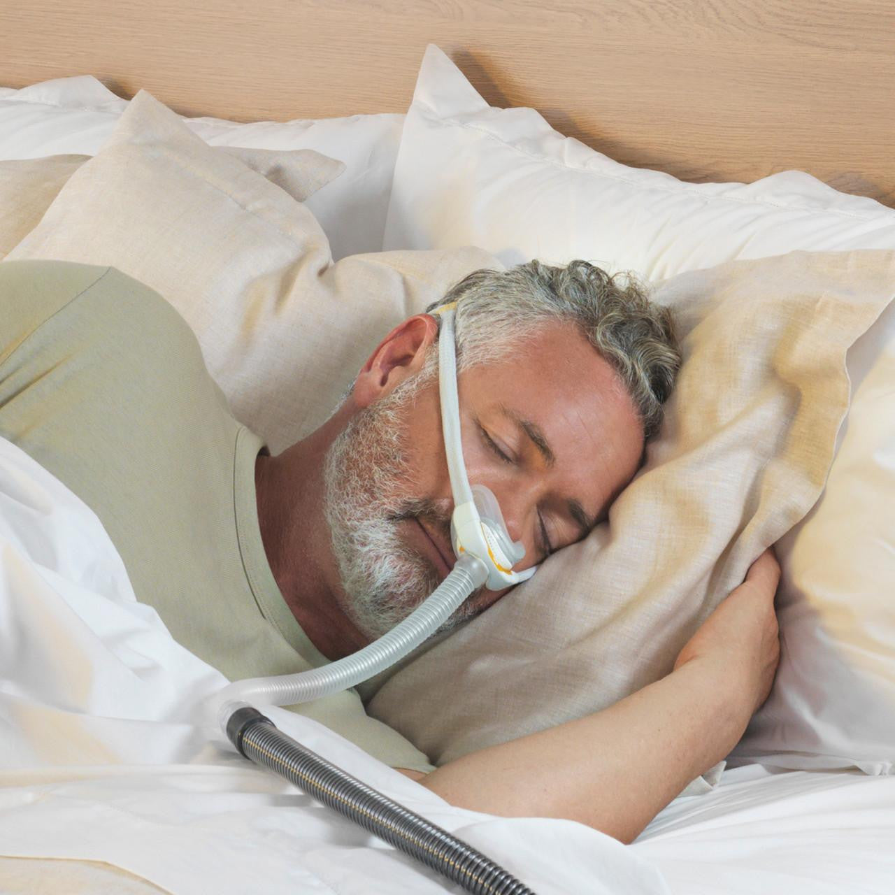 Fisher and Paykel Healthcare Fisher and Paykel Solo Nasal Interface- Individual size pack, man sleeping with nasal interface connected to oxygen therapy device.