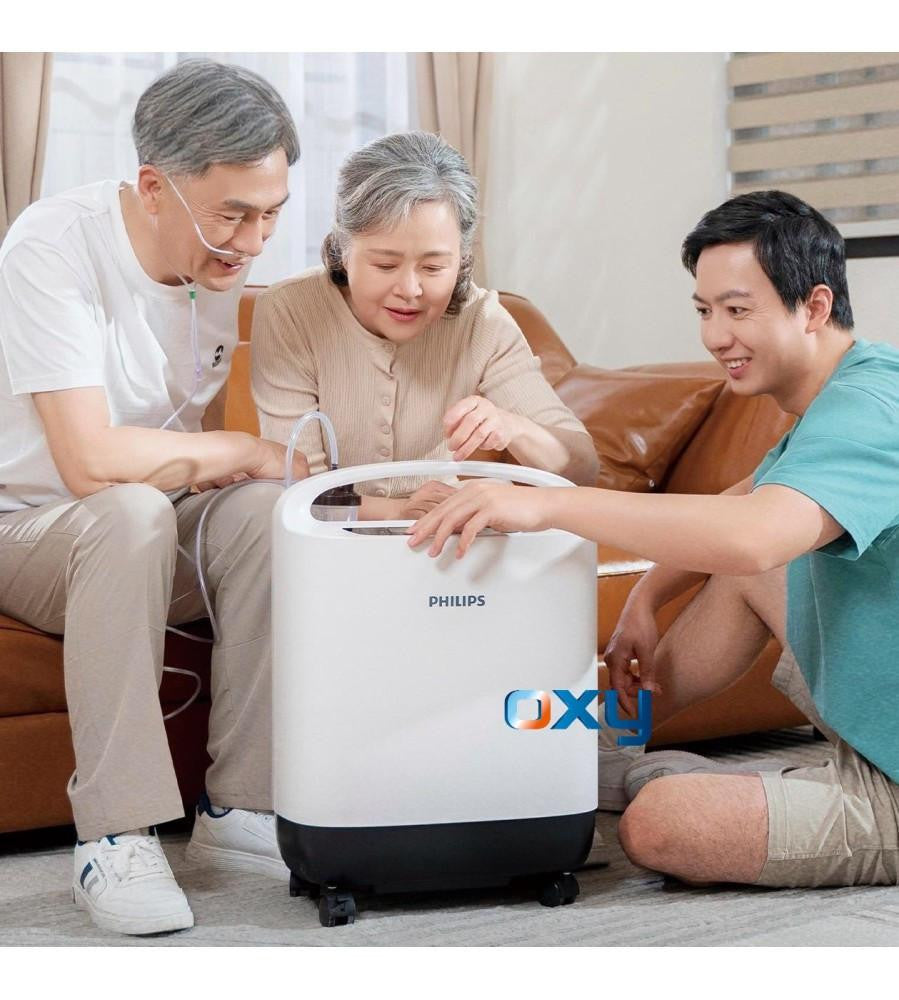 Philips Respironics Philips Oxygenate 5, medical oxygen concentrator with a modern white design, in use at home with three people, an elderly woman and two men, demonstrating its ease of use for respiratory therapy.