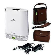 Philips Respironics Simply Go Mini Oxygen Concentrator with standard battery, compact portable device with accessories including carrying case, power cords, and battery pack.