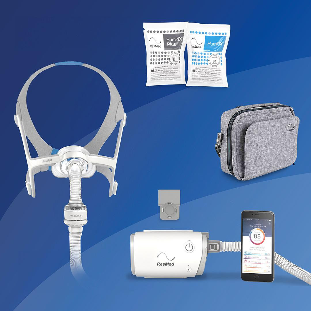 ResMed AirMini - N20 Starter kit, includes a nasal mask with tubing, two humidification packs, a grey carrying case, a white control unit with connected tubing, and a smartphone displaying sleep data.