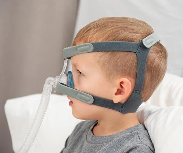 Sleepnet MiniMe 2 pediatric Nasal Mask, a child wearing a nasal mask with straps around the head for sleep therapy.
